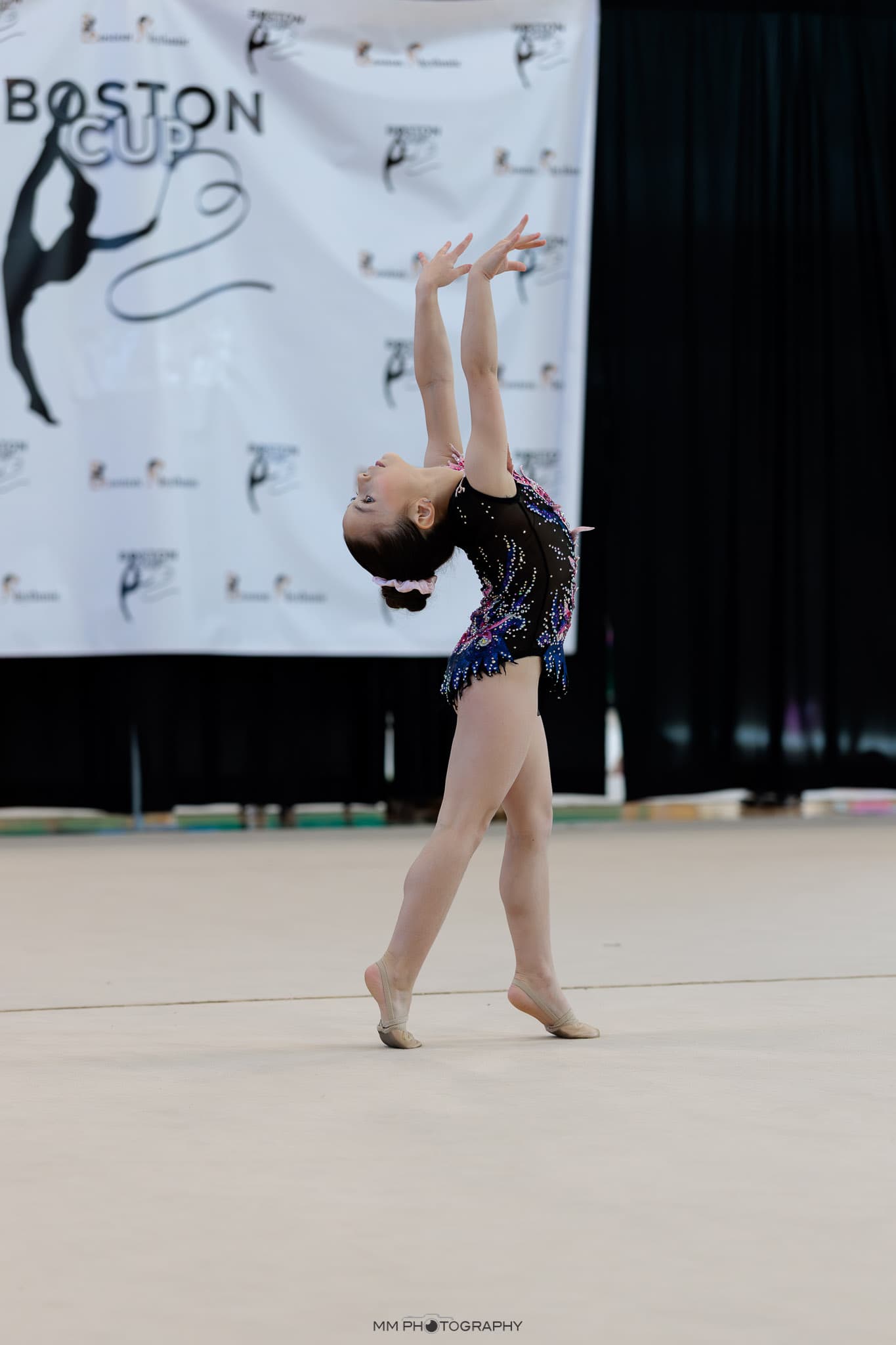A gymnast in a deep backbend during a floor routine at Boston Cup