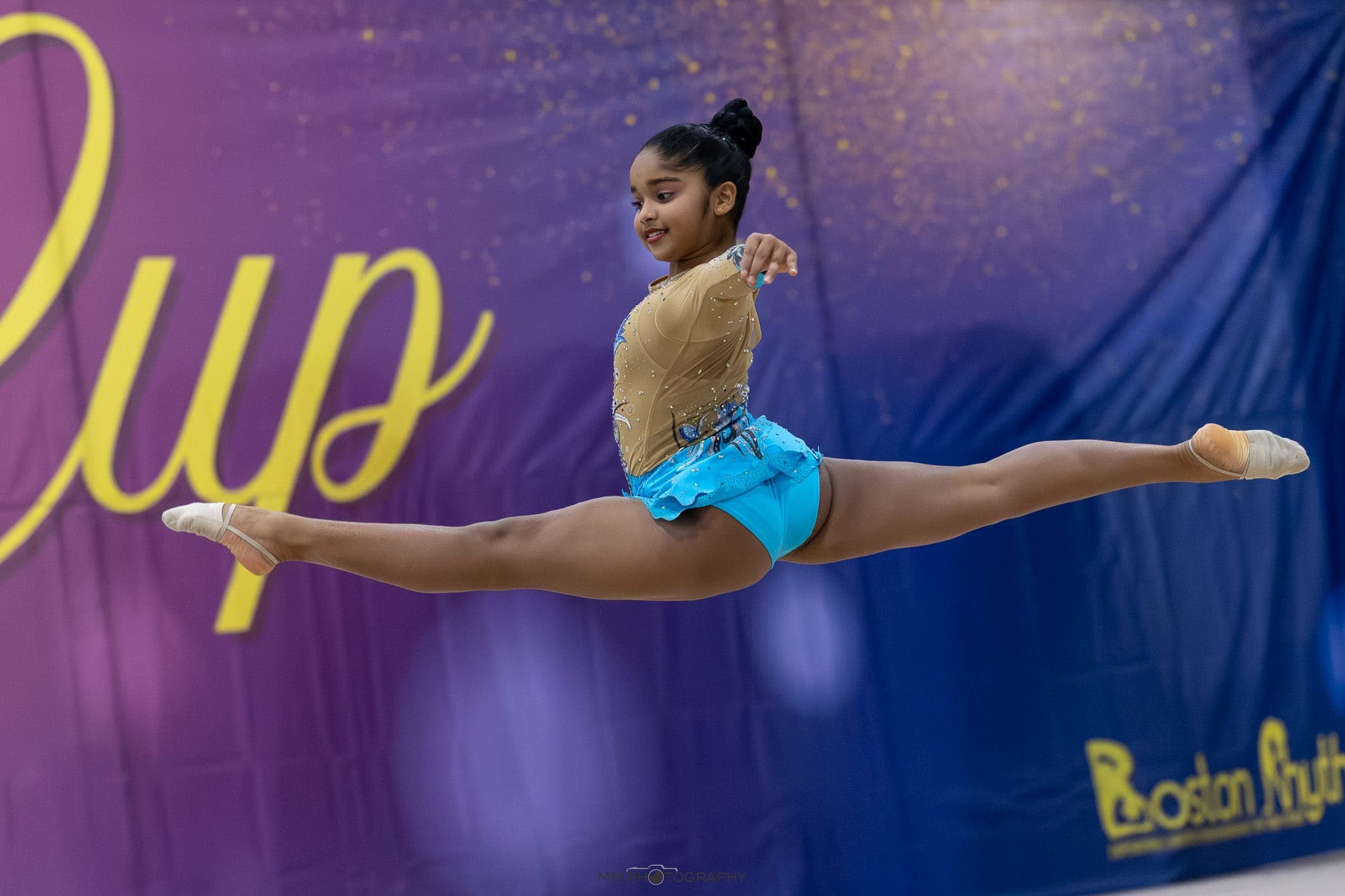 A gymnast in a full split leap during a floor routine