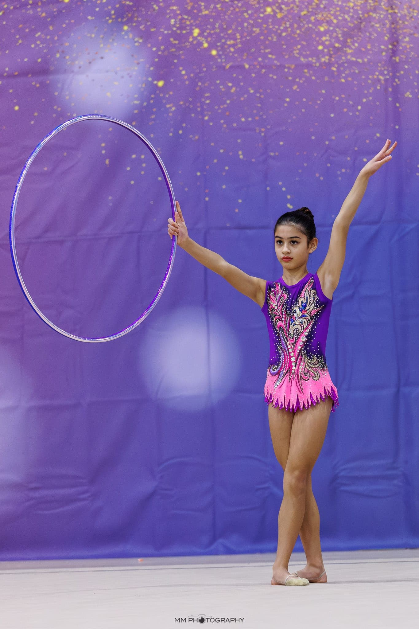 A gymnast presenting a hoop with one arm raised