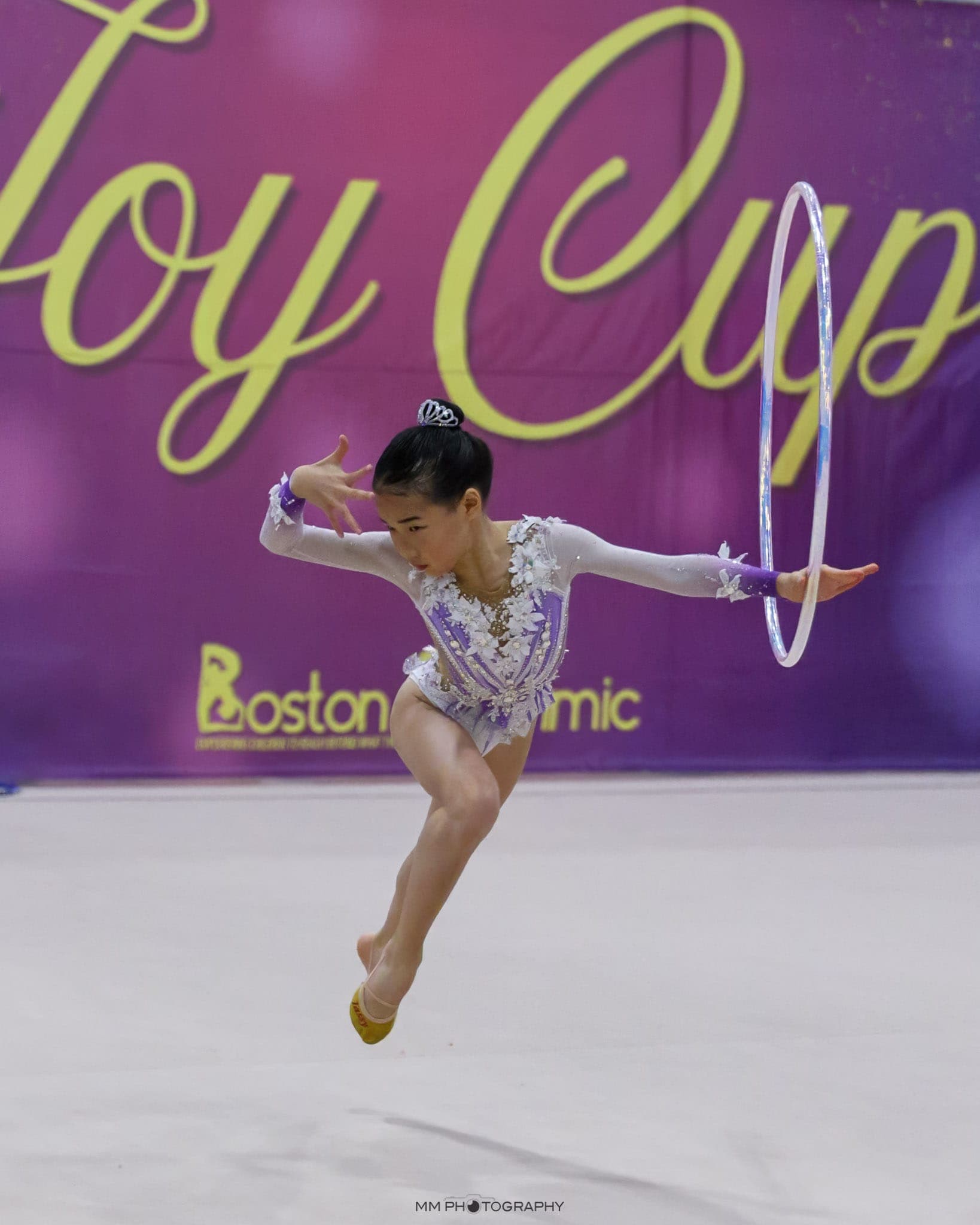 A gymnast leaping with a hoop at the Joy Cup