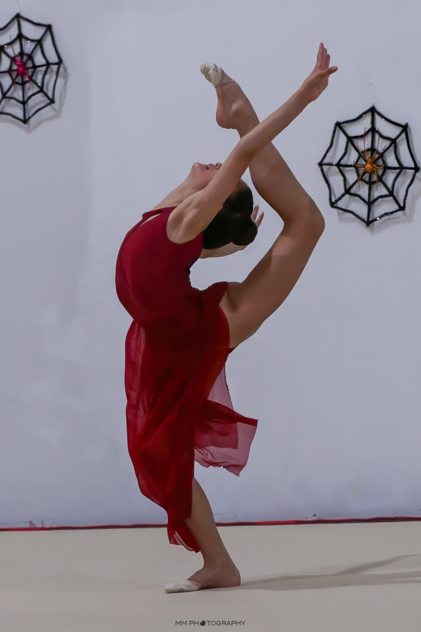 A dancer in a flowing red dress in a deep standing backbend